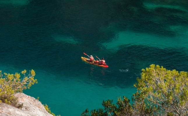 Una familia en kayak per les aigües de la cala Macarelleta, Menorca