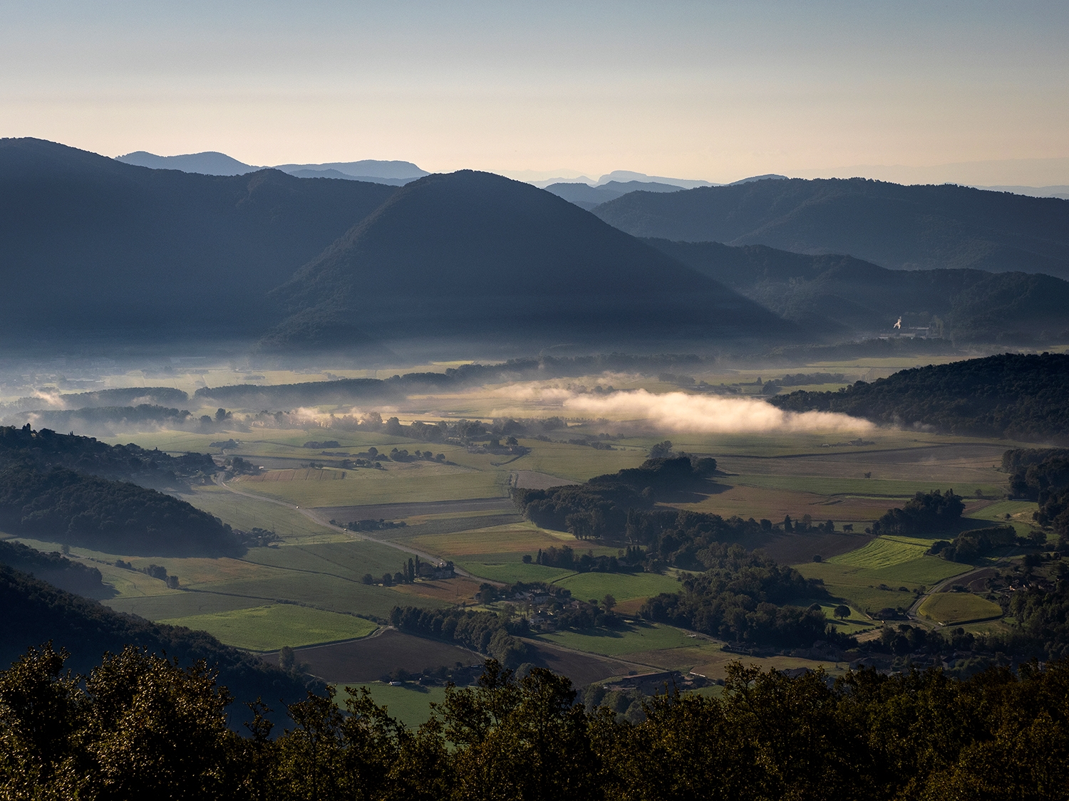 Panoràmica de la vall d’en Bas, despertant-se entre la boira