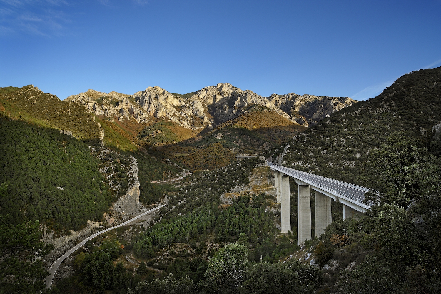 Les penyes Altes de Moixeró es miren des de dalt el viaducte que supera el torrent del Bac de Diví. Aquesta escena es pot albirar des del mirador  del mateix nom, a Bagà